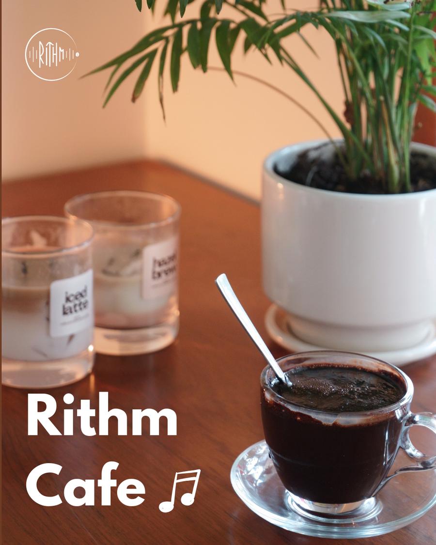 Black coffee and a plant on a wooden table at Rithm Cafe