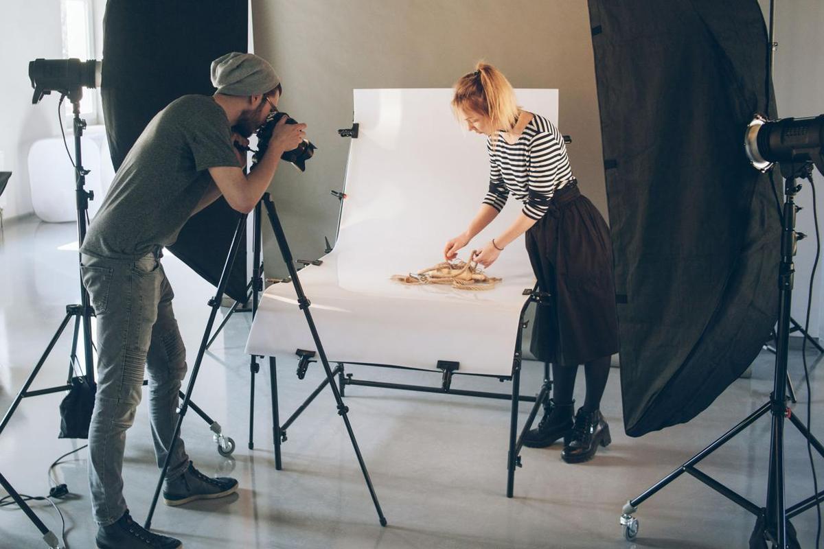 A photographer shooting a product setup in a white studio